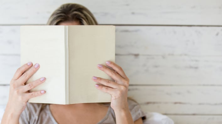 Woman reading a book and covering her face